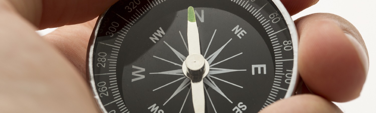 Kompass mit grüner Nadel in einer Hand. Orientierung.