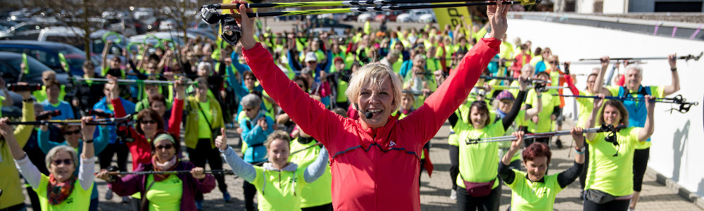 Auf dem Bild zu sehen ist Anke Faller und mehrere Nordic Walking-Läuferinnen und Läufer beim Warming Up vor einem Lauf