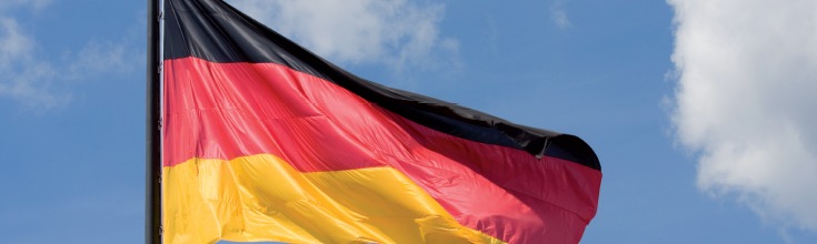 Wehende Deutschlandflagge und im Hintergrund blauer, fast wolkenloser Himmel