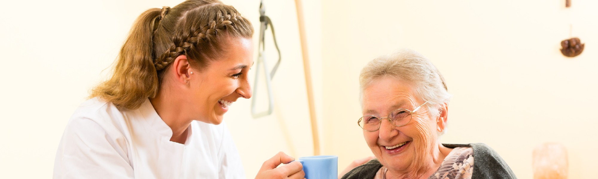 Eine Pflegefachkraft freut sich mit einer Senioren