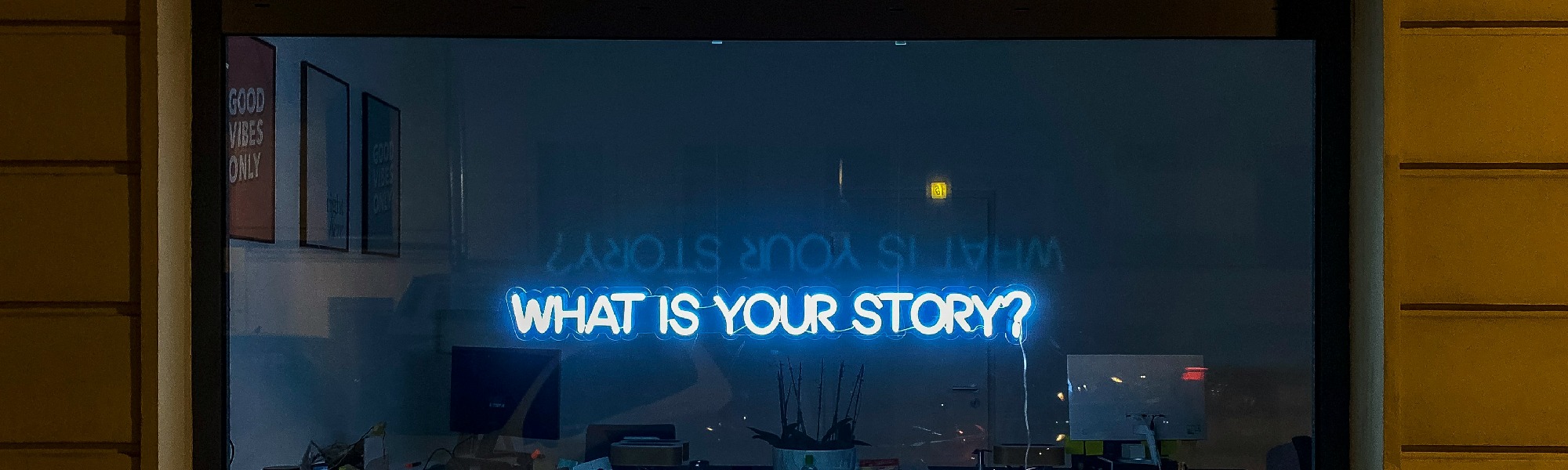 Ein Schaufenster wird von einem Schriftzug erleuchtet. Da steht: What is your story?